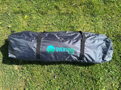 Handy carry bag A grey bag with black straps and a green logo, resting on green grass.